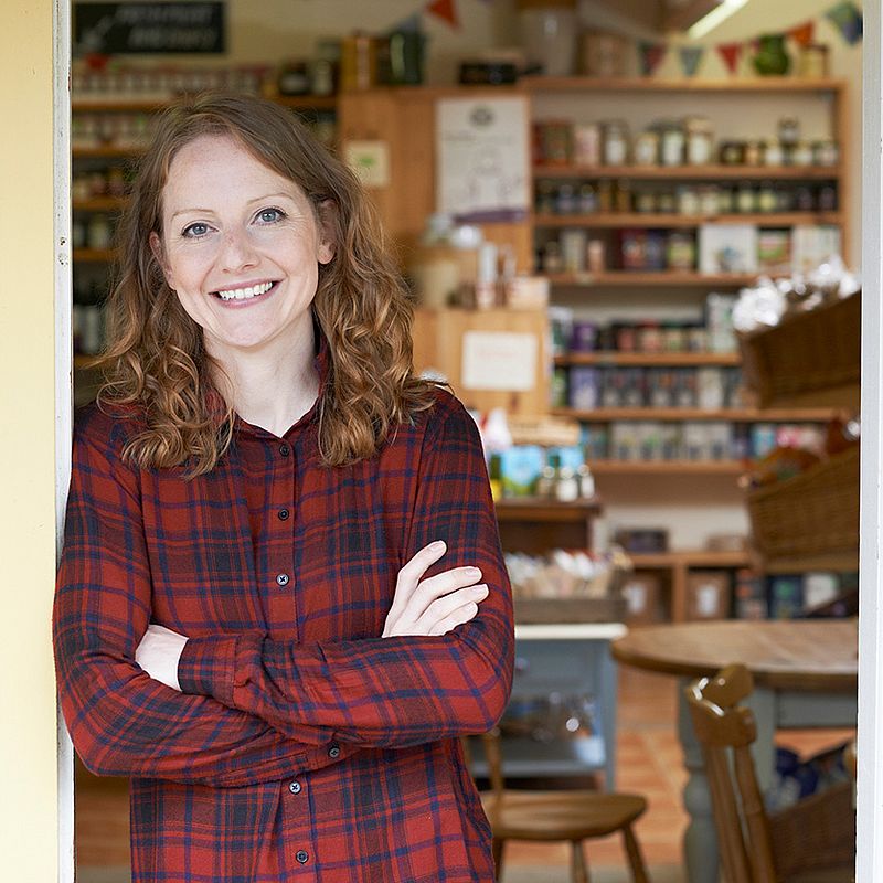 eine frau mit einem rotkarierten hemd steht vor einem geschäft